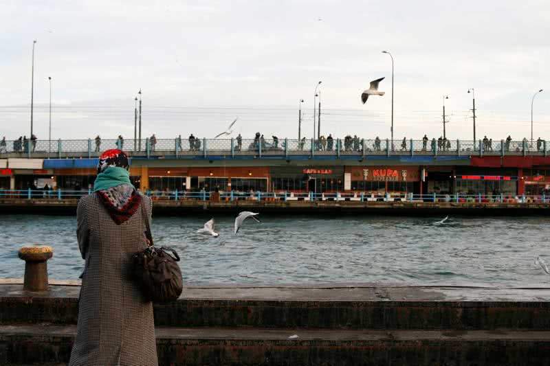 Woman watching seagulls at Galata bridge