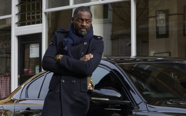 Idris Elba in front of shop and sports car