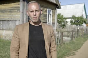 Judge Rinder in front of wooden house