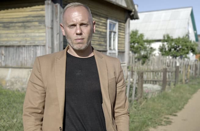 Judge Rinder in front of wooden house