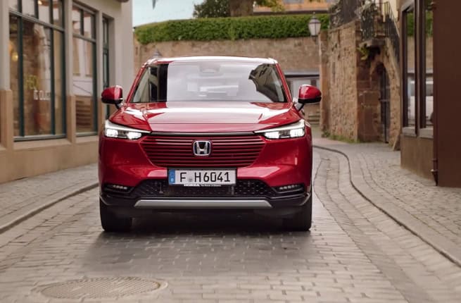 red Honda car passing through old town