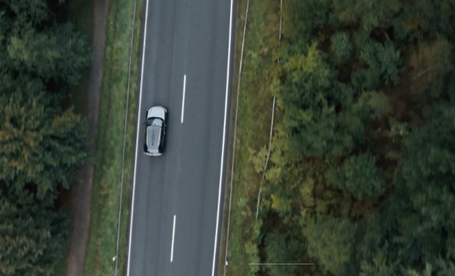 drone shot of a car passing through a forest